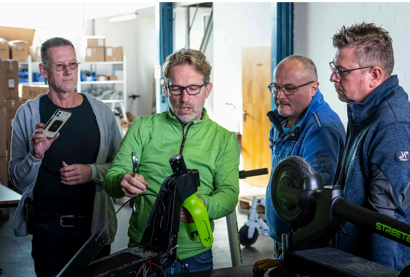 Techniker besprechen sich an einem zerlegten E-Scooter